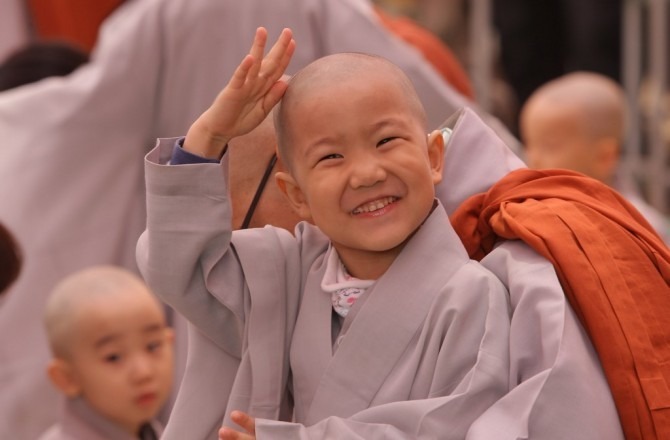 A child rubs his head after a Buddhist monk shaved his hair off during the 'Children Becoming Buddhist Monks' ceremony